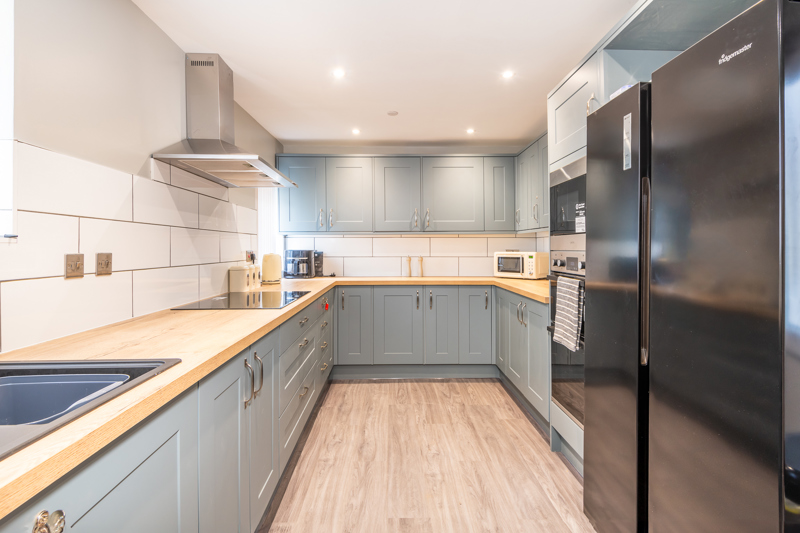 Kitchen at Bayview Lodge with grey shaker units, wood-effect worktops and an American-style fridge freezer