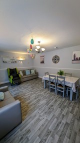 Lounge and dining area at Cedar House with sofas, a dining table and wall clock