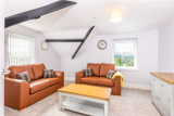 Loft lounge at Brynawel with tan leather sofas, exposed black beams and a window with countryside views