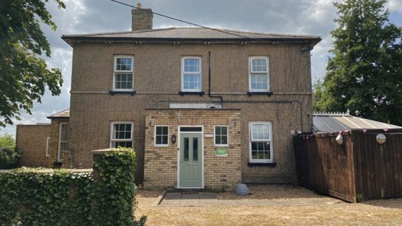 Two-storey yellow-brick exterior of Pathway House with sash windows and a green front door