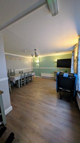 Dining room at Cedar House with a long table, chairs and a wall-mounted TV