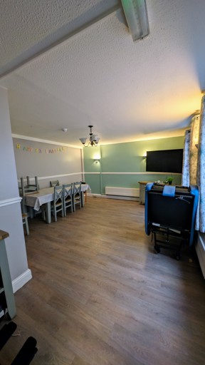 Dining room at Cedar House with a long table, chairs and a wall-mounted TV