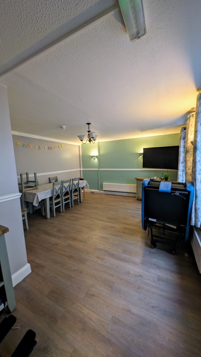 Dining room at Cedar House with a long table, chairs and a wall-mounted TV