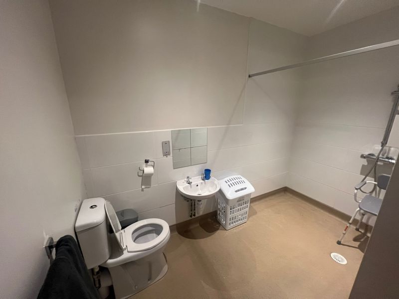 Accessible wet room at Byron Lodge with toilet, basin and shower seat