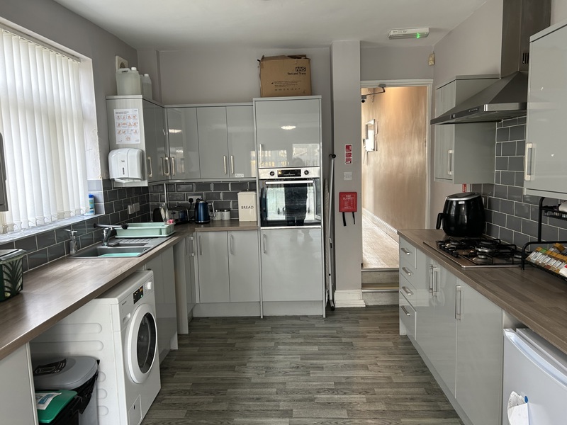Kitchen at Thompson Court with grey gloss units, a gas hob, oven and wood-effect flooring