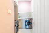 Utility room at Church Road with two washing machines, a sink and storage cupboards
