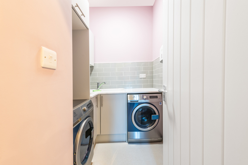 Utility room at Church Road with two washing machines, a sink and storage cupboards