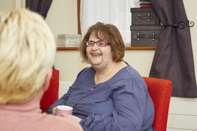 A resident chatting over a cup of tea in a bedroom at Blackwells