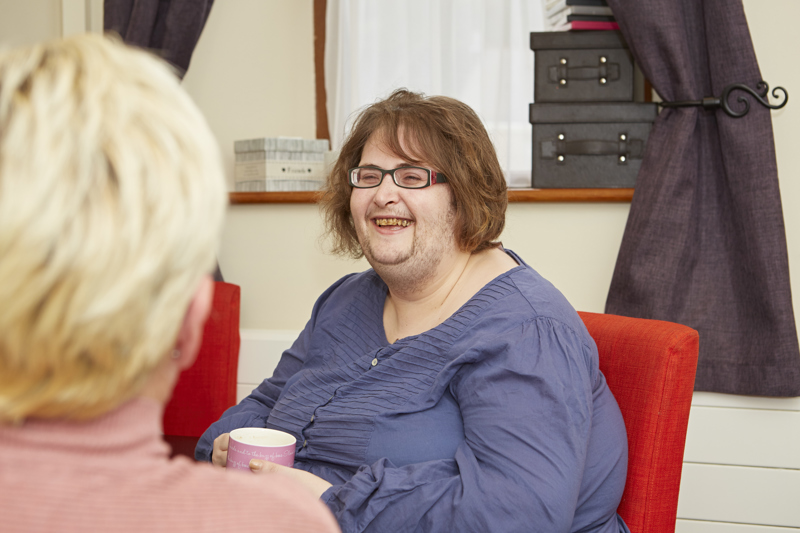 A resident chatting over a cup of tea in a bedroom at Blackwells