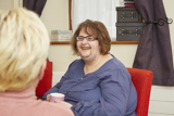 A resident chatting over a cup of tea in a bedroom at Blackwells