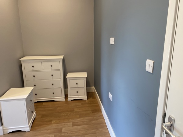 Bedroom at Cranwell Court with a white chest of drawers and bedside cabinets against grey walls